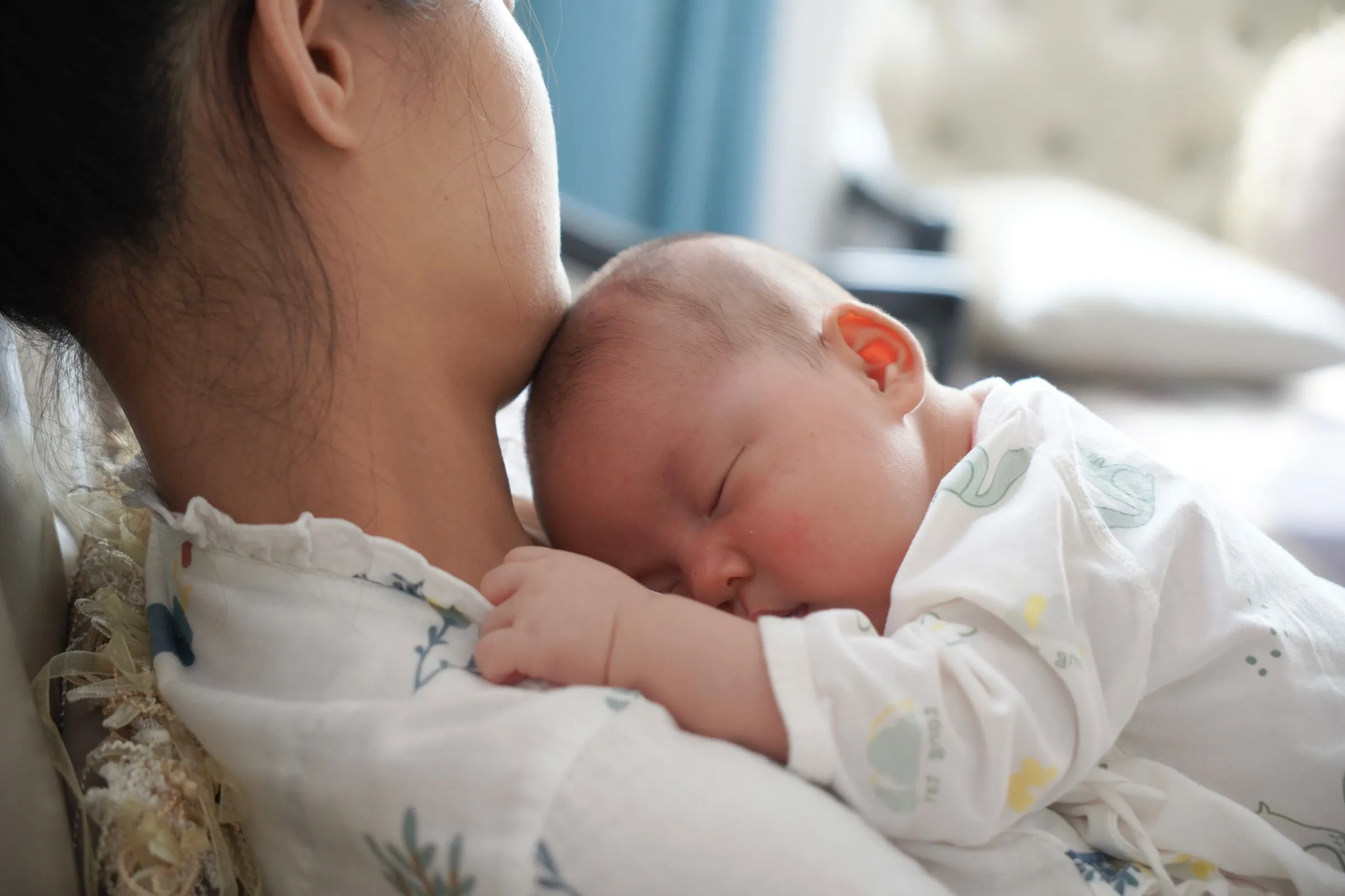 Mãe com o bebê dormindo no colo